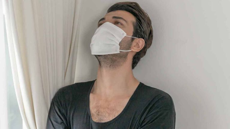 Homem usando máscara com o rosto inclinado para cima com expressão de incerteza