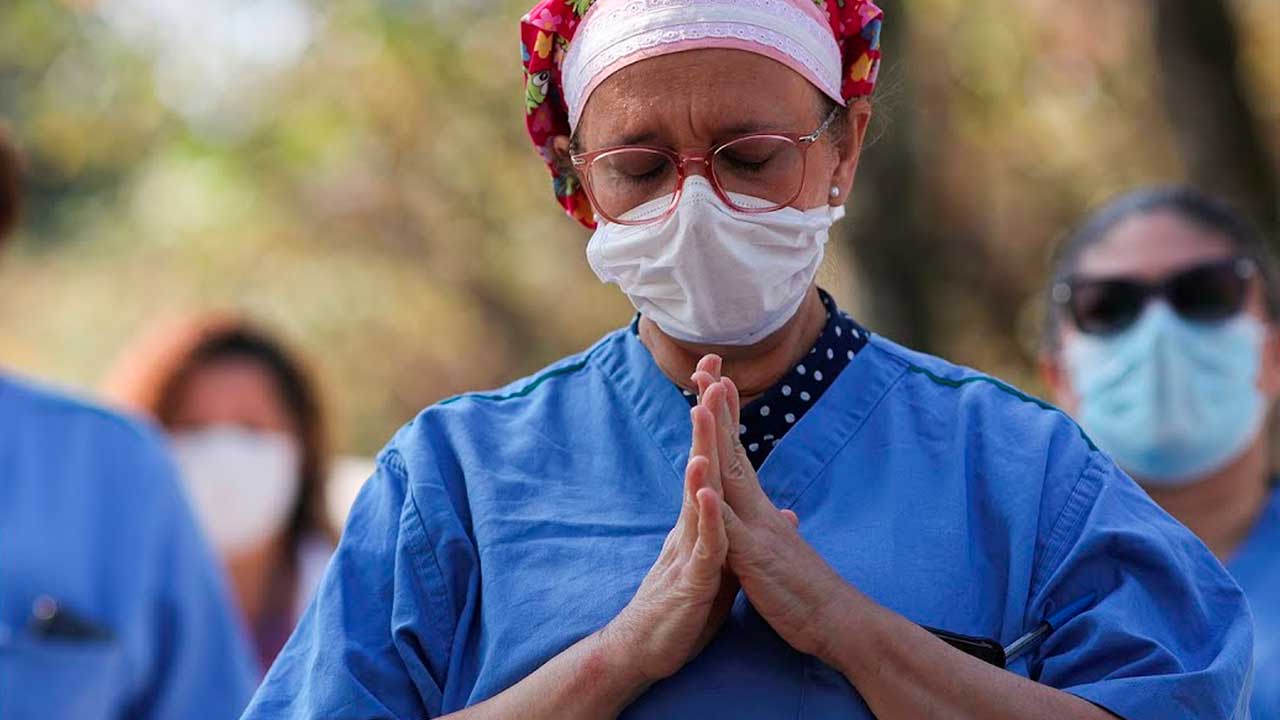 Enfermeira em oração agradecendo pela baixa nos casos de Covid-19