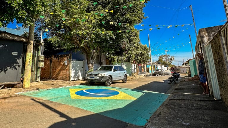 Morador resgata tradição, pinta asfalto e enche rua de bandeiras para a Copa no Água Limpa em João Pinheiro